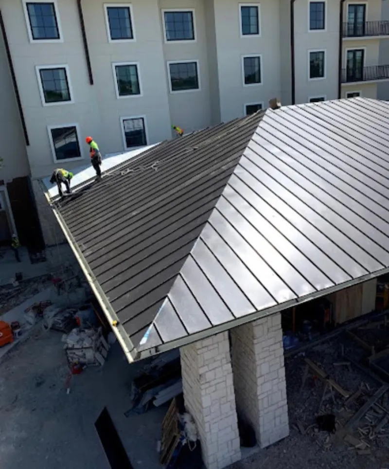 Crew installing standing seam metal roof panels on a commercial project in Lantana